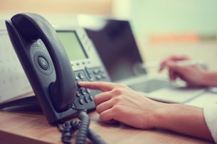 professional services worker dials phone number on landline phone