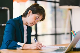 professional services worker sits at desk and writes